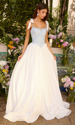 A person wearing a Denim Blue/White Ava Presley 43128 ball gown with a bodice featuring white floral embroidery and ribbon straps, paired with a solid white skirt.