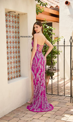 A woman models the Strapless Long Sequin Prom Dress: Primavera 4314, a fitted sequin gown with silver embellishments, while posing outdoors by a tiled wall and black metal gate.
