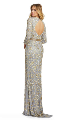 A woman stands looking over her shoulder, wearing the Long Formal Dress 4316 by Mac Duggal—an elegant floor-length platinum gown with gold sequin embellishments and a circular open back.