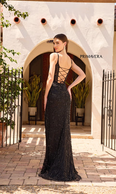 A woman wearing the Primavera 4317 Lace-Up Long Lace Prom Dress stands outdoors before an arched doorway framed by lush plants and iron gates.