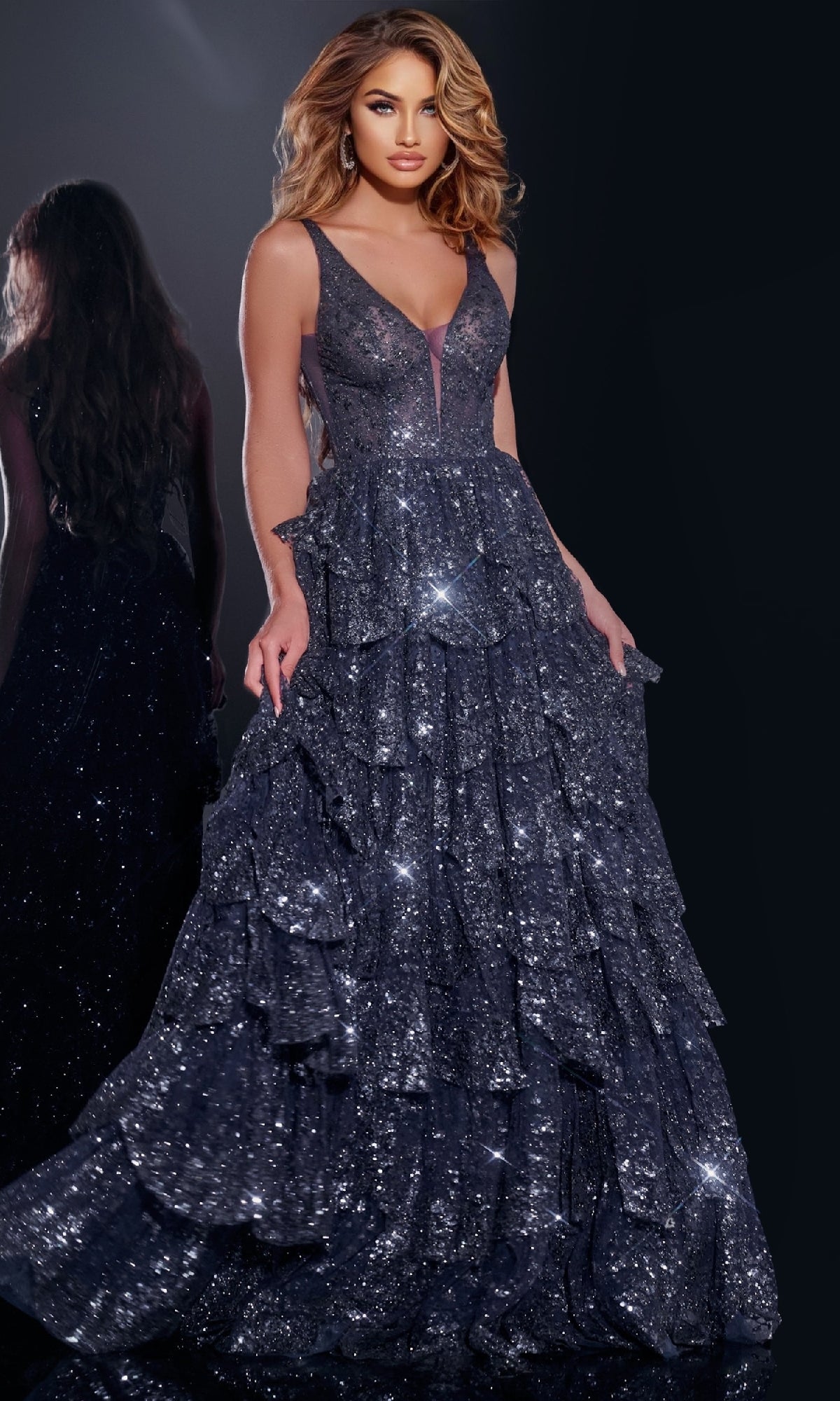 A woman in the Jovani 43198 Ruffled Long Glitter Prom Dress, a sleeveless deep v-neck dark blue gown with sparkling ruffles, stands against a dark background with her reflection visible behind her.