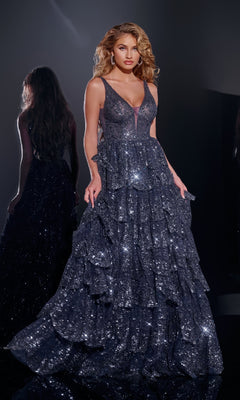 A woman stands in a dark room wearing the Jovani 43198 Ruffled Long Glitter Prom Dress in navy. The floor-length gown sparkles with layered ruffle details, her hair styled in loose waves, and her reflection visible behind her.