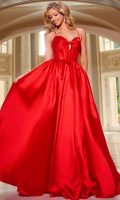 A woman stands indoors, holding out one side of her bright red Satin Prom Ball Gown (Jovani 43199), featuring a floor-length full skirt and fitted corset bodice.
