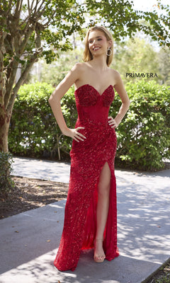 A woman wearing the Strapless Long Sequin Prom Dress: Primavera 4321, featuring a thigh-high slit and sweetheart neckline, stands smiling outdoors on a sidewalk with the "PRIMAVERA" brand name in the background.