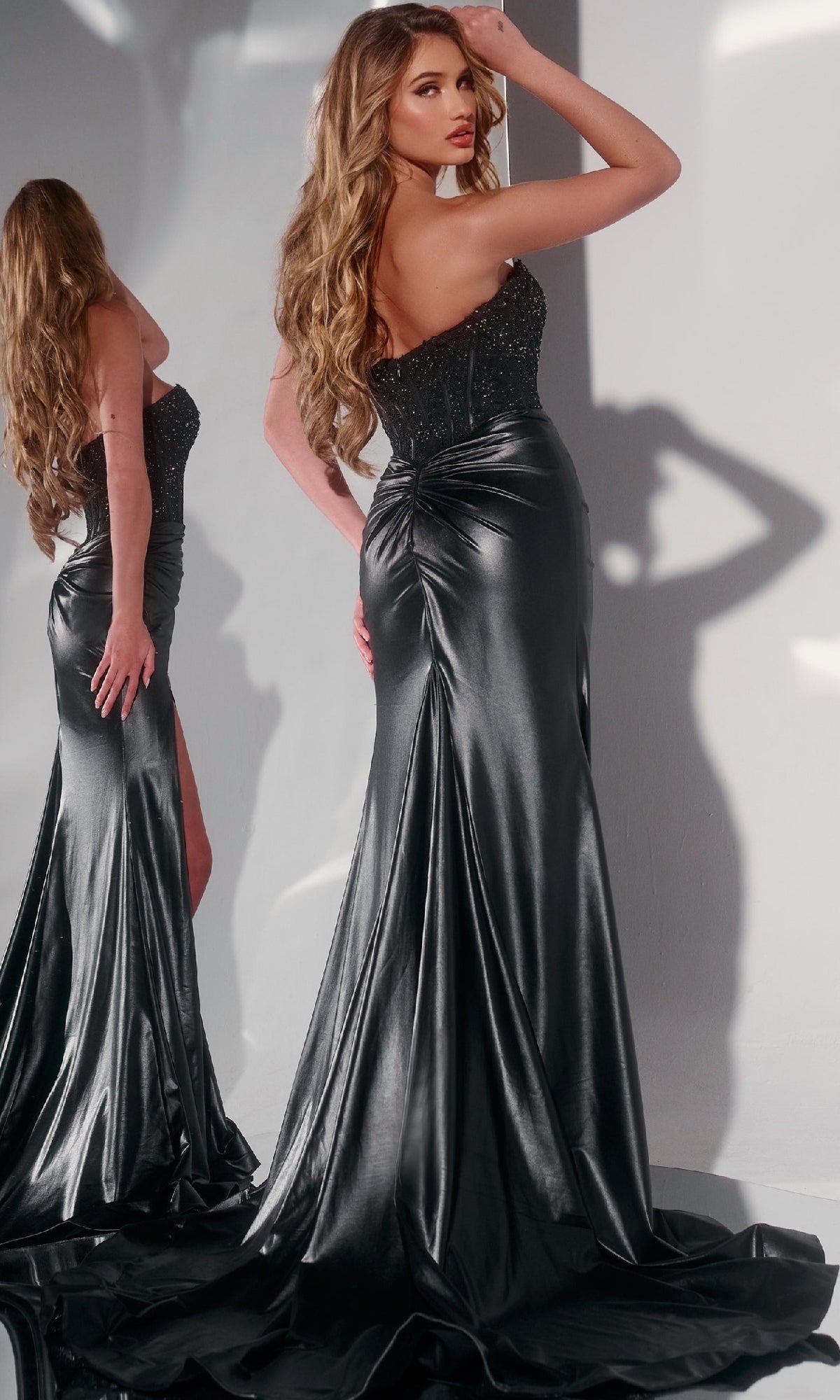 A woman poses by a mirror in the Jovani 43267 Strapless Tight Long Prom Dress, highlighting its flowing fabric, fitted silhouette, and intricate beaded embroidery.