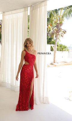 A woman wears the shimmering Primavera 4329 long prom dress, featuring a one-shoulder design, side cutout, and thigh-high slit, standing near white curtains and palm trees with "PRIMAVERA" in the background.