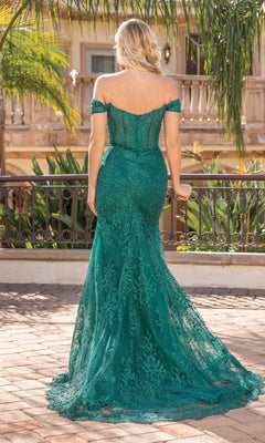A woman stands outdoors, facing away, wearing the Off-the-Shoulder Long Formal Prom Dress 4332 in green, with tropical plants and a building in the background.