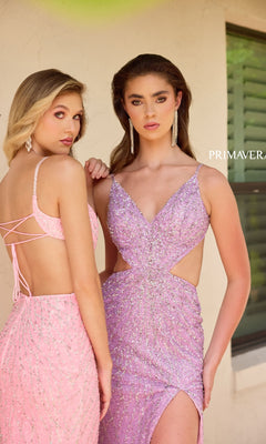 Two women stand side by side in front of a building, both wearing Primavera 4334 Long Prom Dresses—one in pink and one in lavender with side cut-outs—posing for the camera.