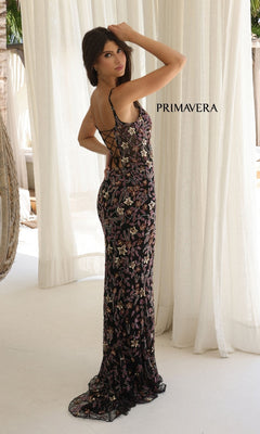 A woman stands indoors before light curtains wearing the Sequin-Floral Long Prom Dress: Primavera 4336, a floor-length, sleeveless dress with lace-up open-back and floral sequin design. "PRIMAVERA" is displayed on the curtain behind her.