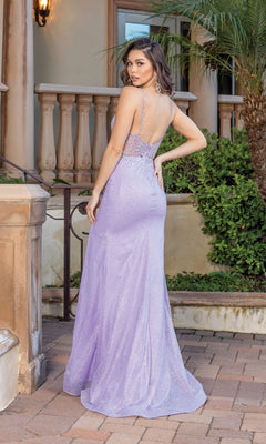A woman stands outdoors on a brick path near greenery, facing away from the camera, wearing the Sheer-Waist Glitter-Bodice Long Prom Dress 4348—a light purple formal gown with thin straps and a sparkling bodice.