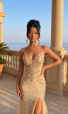 A woman in the Embellished Long Mermaid Formal Prom Dress 4352 stands on a stone balcony with columns, enjoying a scenic sunset view.