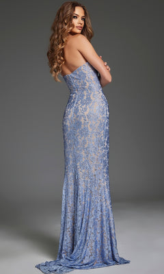 A woman with long wavy hair models the Jovani 43753 long prom dress with a one-shoulder lace design and leg slit, standing with arms crossed and facing away from the camera.