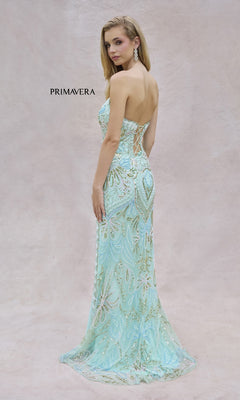 A woman wearing the Strapless Long Beaded Prom Dress: Primavera 4382 with a lace-up back stands against a pale background. This formal gown boasts intricate patterns and a floor-length hem for an elegant appearance.