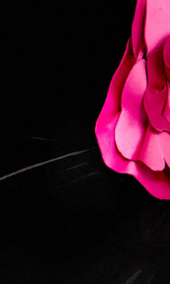A close-up of bright pink ruffled fabric, reminiscent of floral applique details on the Jovani 43886 Long Prom Dress, set against a deep black background.