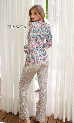 A woman stands indoors facing away, wearing the Long Sequin Formal Jumpsuit: Primavera 4388. Light-colored curtains and a wooden floor are visible, with "PRIMAVERA" displayed on the image.