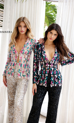 Two women stand side by side in the Primavera 4388 Long Sequin Formal Jumpsuit—one in silver and pastel, the other in black multicolor—with sheer white curtains as a backdrop.