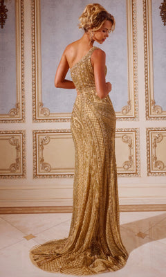 A woman in the Jovani 43927 Long Prom Dress, featuring gold beads, a one-shoulder neckline, and a floor-length silhouette, stands in an ornate room with her back to the camera.