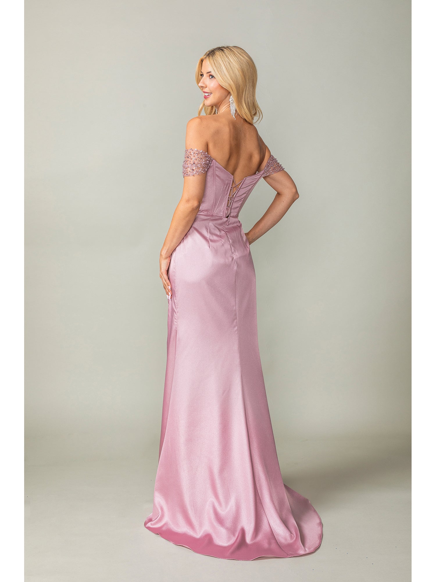 A woman models the Off-the-Shoulder Long Prom Dress 4401 with beaded sleeves in pink satin, standing and looking over her shoulder against a plain backdrop.