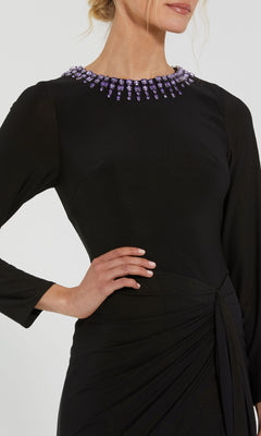 A woman stands with one hand on her hip, wearing the Mac Duggal 44069 Bead-Neckline Long Formal Dress featuring modest long sleeves, a fitted waist, and a beaded purple neckline.