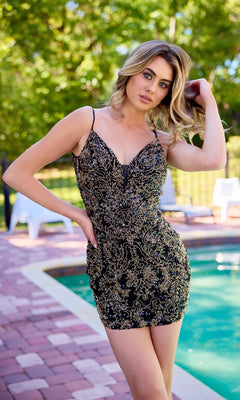 A woman poses poolside in the Primavera 4414—a short black and gold patterned bodycon homecoming dress with a low scoop open back—amid lush greenery and outdoor furniture.