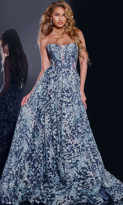 Wearing the Jovani 44151 long prom dress, a woman stands against a dark background. The strapless navy gown features a corset bodice and intricate silver embroidery, with her reflection visible.