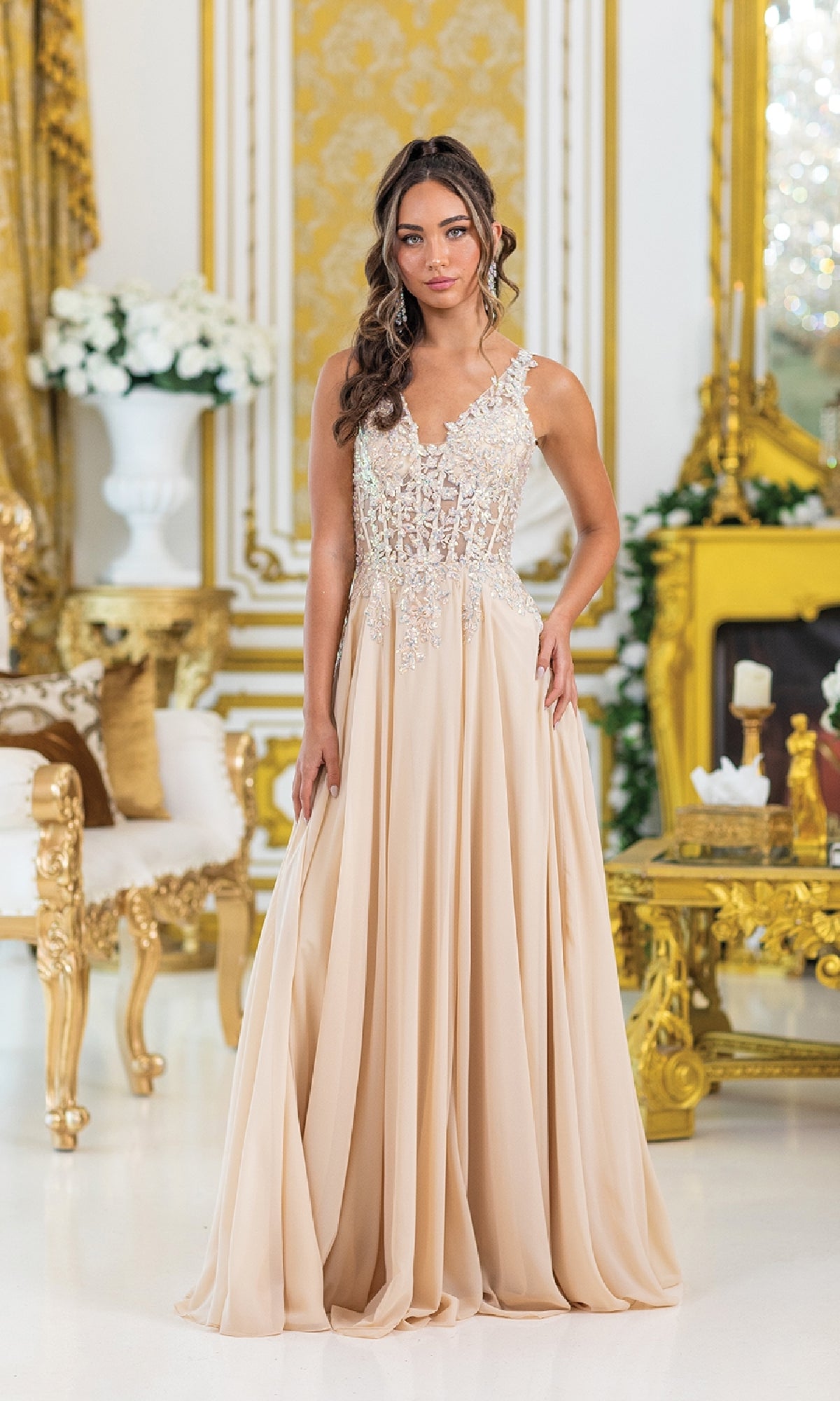 A woman in the Dancing Queen 4446 Lace-Up Long A-Line Prom Dress, featuring intricate lace and bead-embroidered corset details, stands in an ornate, gold-accented room.