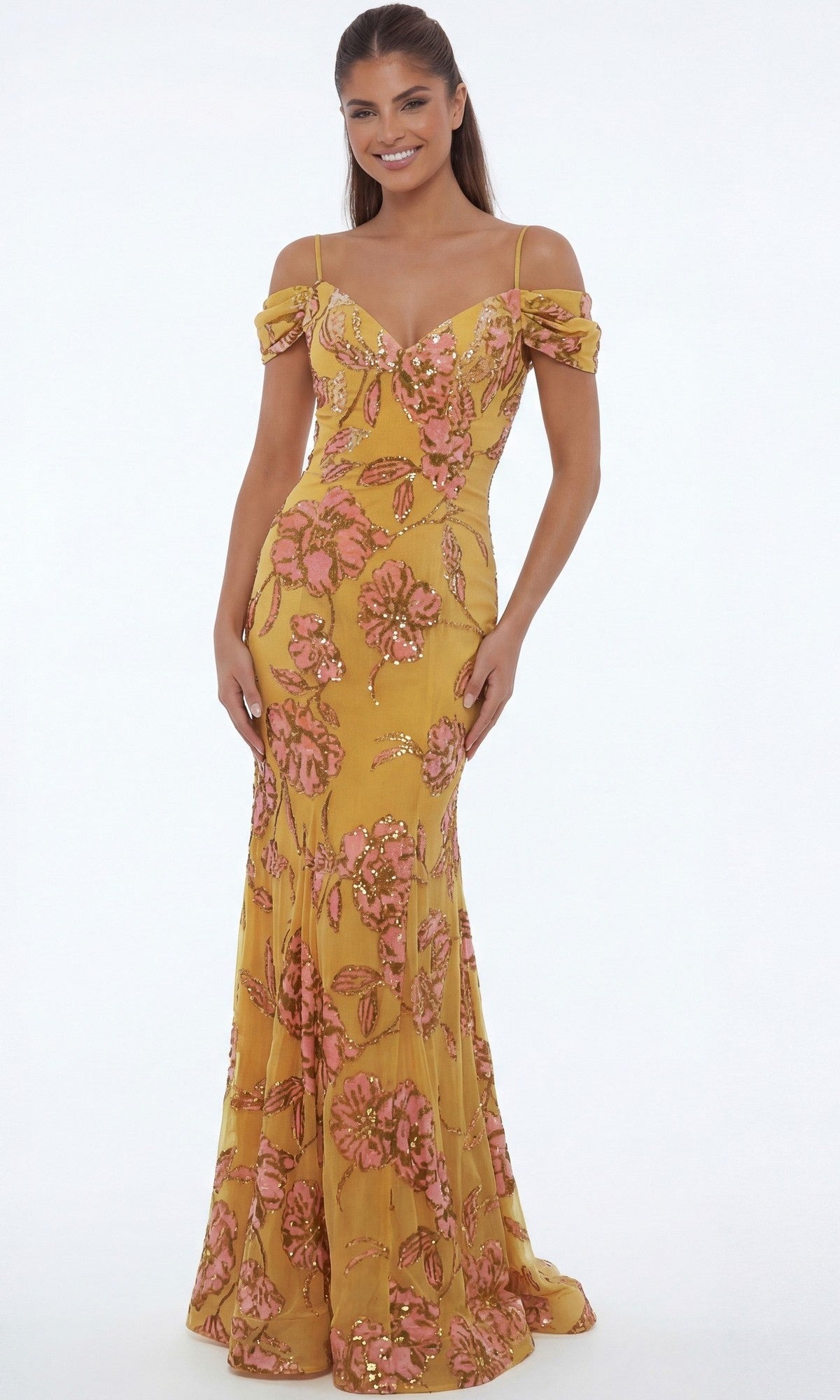 A woman wearing the Jovani 44652 long formal dress in yellow/multi, featuring a floor-length, off-the-shoulder design with pink floral embroidery and sequin accents, stands against a plain white background.