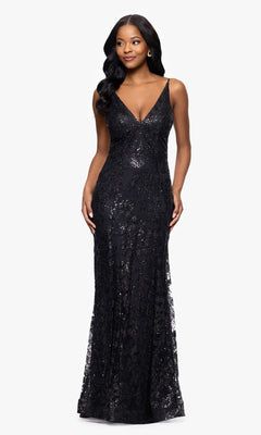 A woman stands against a plain white background wearing the Blondie Nites 4501BN Long Sequin-Print Prom Dress, featuring a deep V-neckline and strappy back.