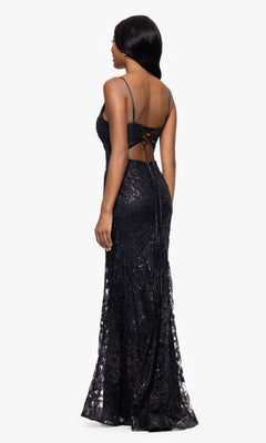 A woman stands facing away, wearing the Blondie Nites 4501BN—a long sequin-print prom dress with thin straps, open back, and lace-up detailing.