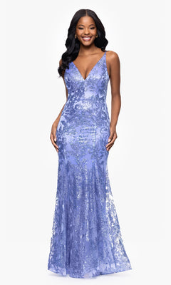A woman stands smiling against a white background, wearing the Blondie Nites 4501BN long sequin-print prom dress with a sleeveless V-neckline and strappy-back detail.