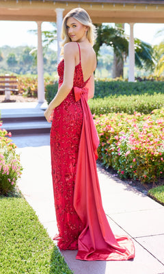 A woman wearing the Primavera 4503 long prom dress with beaded embellishments and a sheath silhouette stands on a garden pathway, looking over her shoulder.