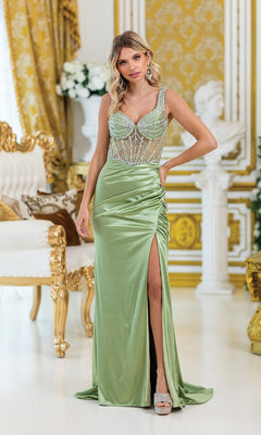 A woman stands indoors in a Sheer-Corset Long Prom Dress, Dancing Queen 4505, featuring a beaded bodice and thigh-high slit, surrounded by ornate gold and white decor.