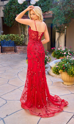 A woman wearing the Primavera 4532 long prom dress stands outdoors on a stone patio, looking over her shoulder and surrounded by flowers and plants.