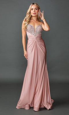 A woman poses against a gray background wearing the Dancing Queen 4553, a lace-up long pink prom dress featuring a twist-front, sparkly deep V-neck bodice, thin straps, and beaded open back.