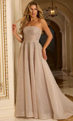 A woman wears a Jovani 45788 Long Prom Dress in Cafe with beaded grid texture, standing indoors near a decorative wall, marble floors, and an arched hallway in the background.
