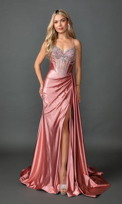 A woman in the Dancing Queen 4581 long prom dress in rose gold, featuring a jeweled corset bodice, thin straps, high slit, and a flowing satin sheath skirt, with long wavy blonde hair, standing against a gray background.