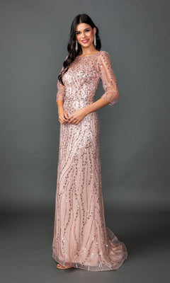 A woman wearing the Long Prom Dress: Dancing Queen 4588 in rose gold, featuring sequin embellishments and sheer sleeves, with long wavy hair, standing against a plain dark background.