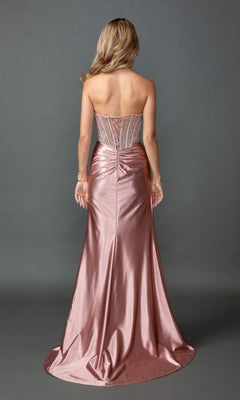 A woman stands with her back to the camera, wearing the Long Prom Dress: Dancing Queen 4593—a metallic pink, floor-length gown highlighted by a fitted, sheer corset bodice and ruched detailing on the back.
