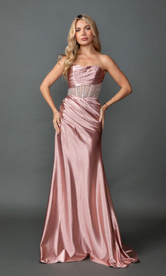 A woman stands against a plain gray background wearing the Long Prom Dress: Dancing Queen 4593 in rose gold, which features a long strapless silhouette with a beaded waistband, a sheer corset bodice, and a satin skirt.