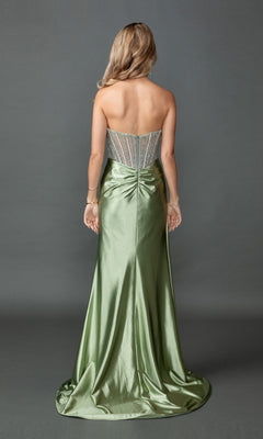 A woman stands facing away on a gray backdrop, wearing the Long Prom Dress: Dancing Queen 4593, which features a beaded, sheer corset bodice and a flowing green satin skirt.