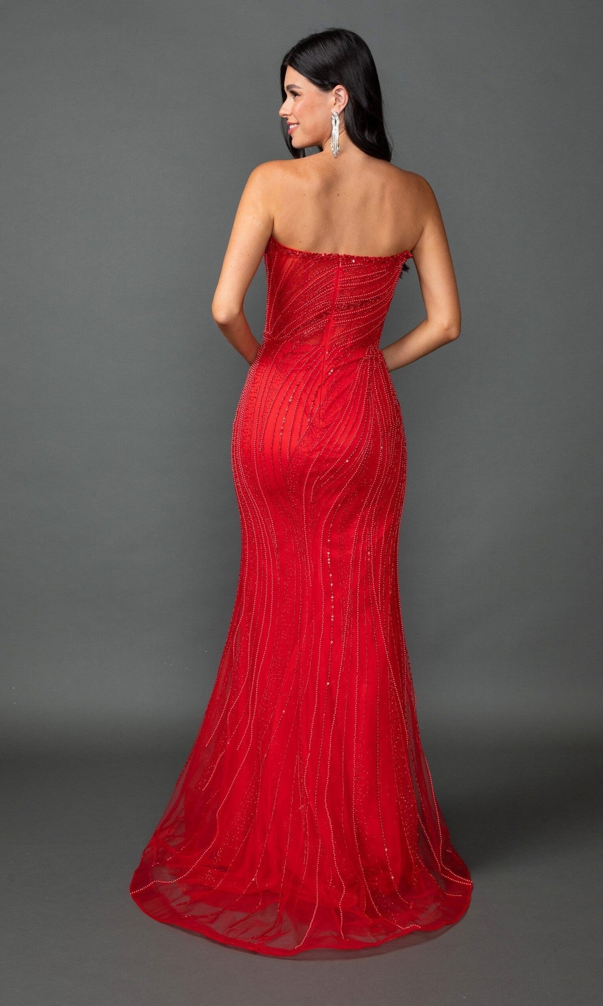 A woman poses elegantly with her back to the camera against a plain gray background, showcasing the Long Prom Dress: Dancing Queen 4597—a fitted, floor-length strapless gown in vibrant red with sparkling bead detailing.