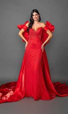 A woman stands in the Long Prom Dress: Dancing Queen 4597, a floor-length, fitted red gown featuring beaded details, dramatic puffed sleeves, and a sweeping train, set against a plain gray background.