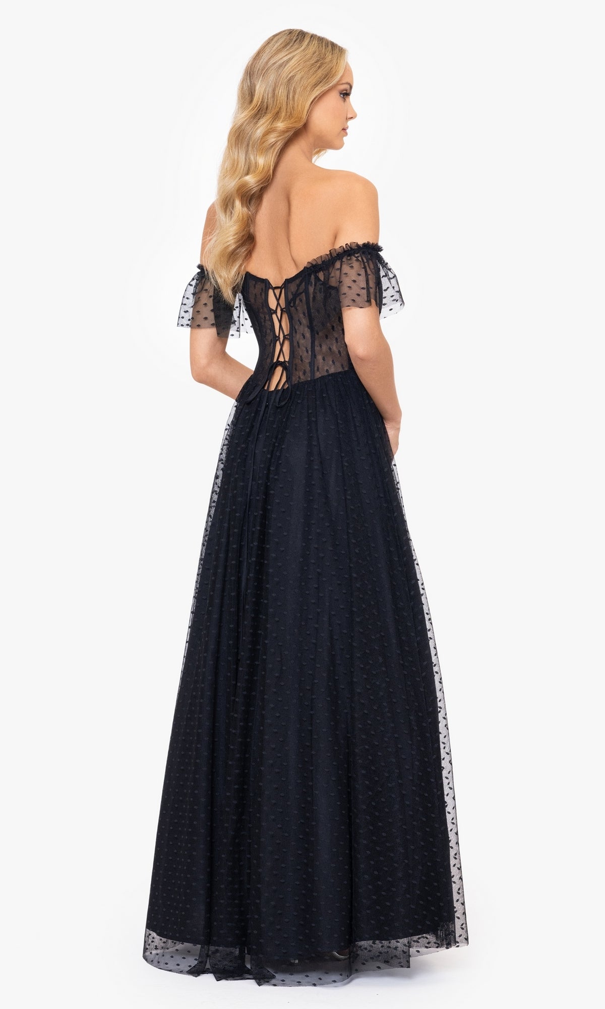 A woman stands with her back to the camera in the Swiss Dot Long Black Lace-Up Prom Dress 4601BN, featuring an off-the-shoulder neckline, lace-up back, and sheer Swiss dot overlay.