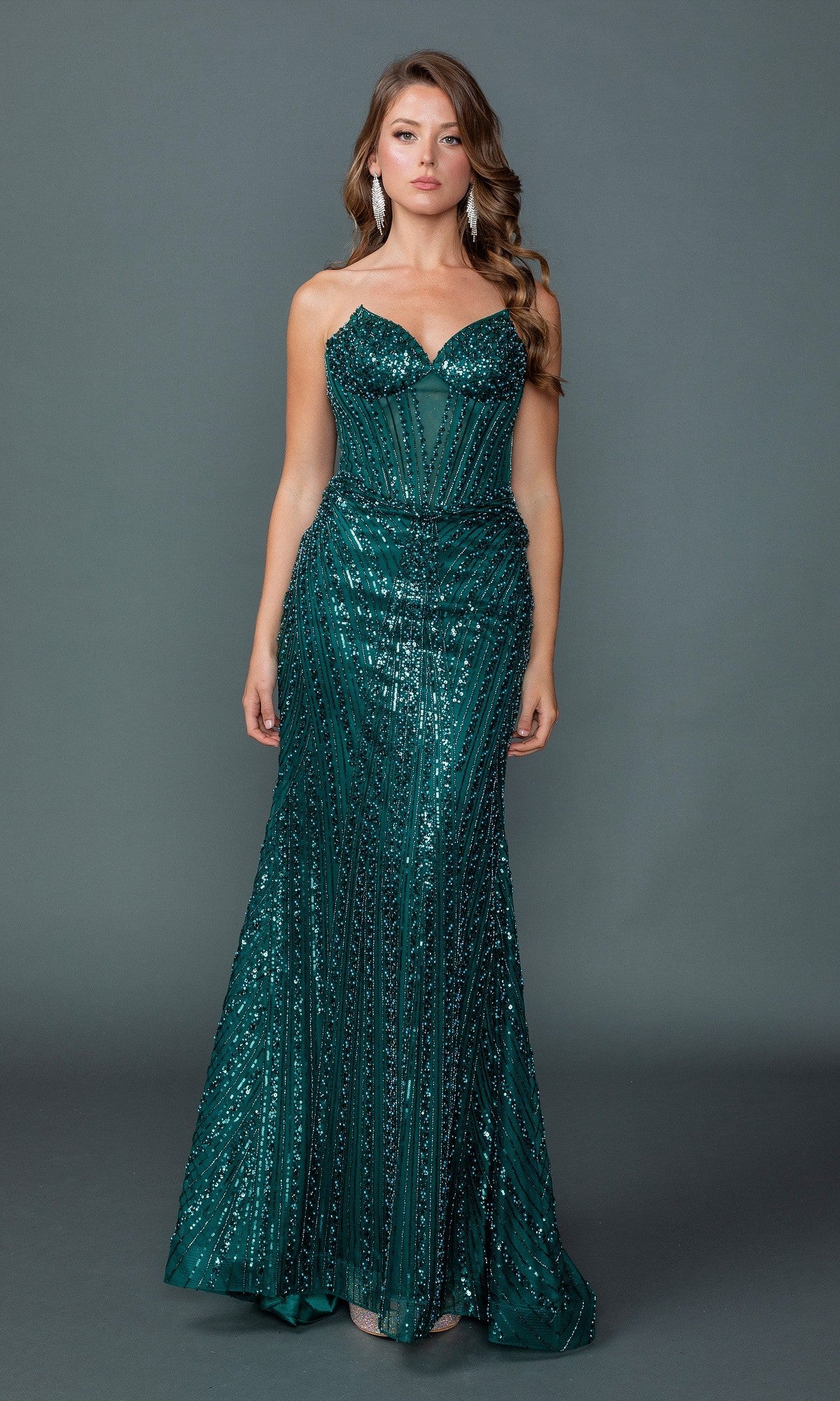 A woman stands against a gray background wearing the Dancing Queen 4606 long prom dress—a fitted, strapless, floor-length gown in hunter green with sequins and beading.