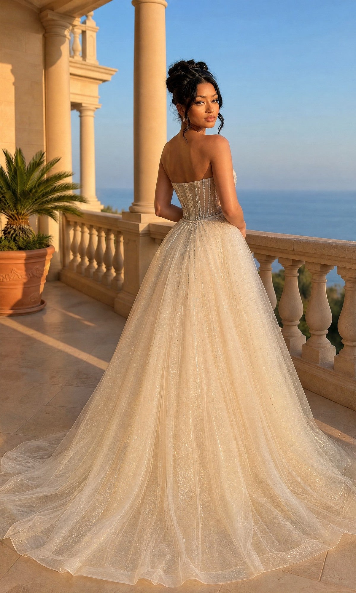 A woman in the Long Prom Dress: Dancing Queen 4607 with a glitter tulle overskirt stands on a sunlit terrace, the sea and grand columned architecture behind her.