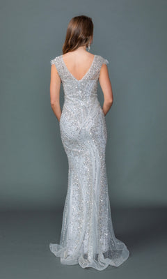 A woman stands with her back to the camera, showcasing the Dancing Queen 4613 long prom dress—a floor-length silver sequin evening gown featuring cap sleeves and a sophisticated v-neckline—set against a plain gray backdrop.