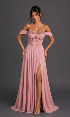A woman wears the Long Prom Dress: Dancing Queen 4615 in blush, showcasing its off-the-shoulder neckline, embellished corset bodice, and a flowing a-line skirt with a high slit, standing gracefully against a plain dark background.