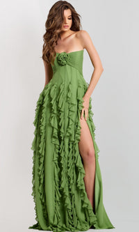 A woman wears the Jovani 46379 Long Prom Dress in light green, with ruffle details, a ruched bodice adorned with a floral accent, and a high slit, posing against a plain backdrop.