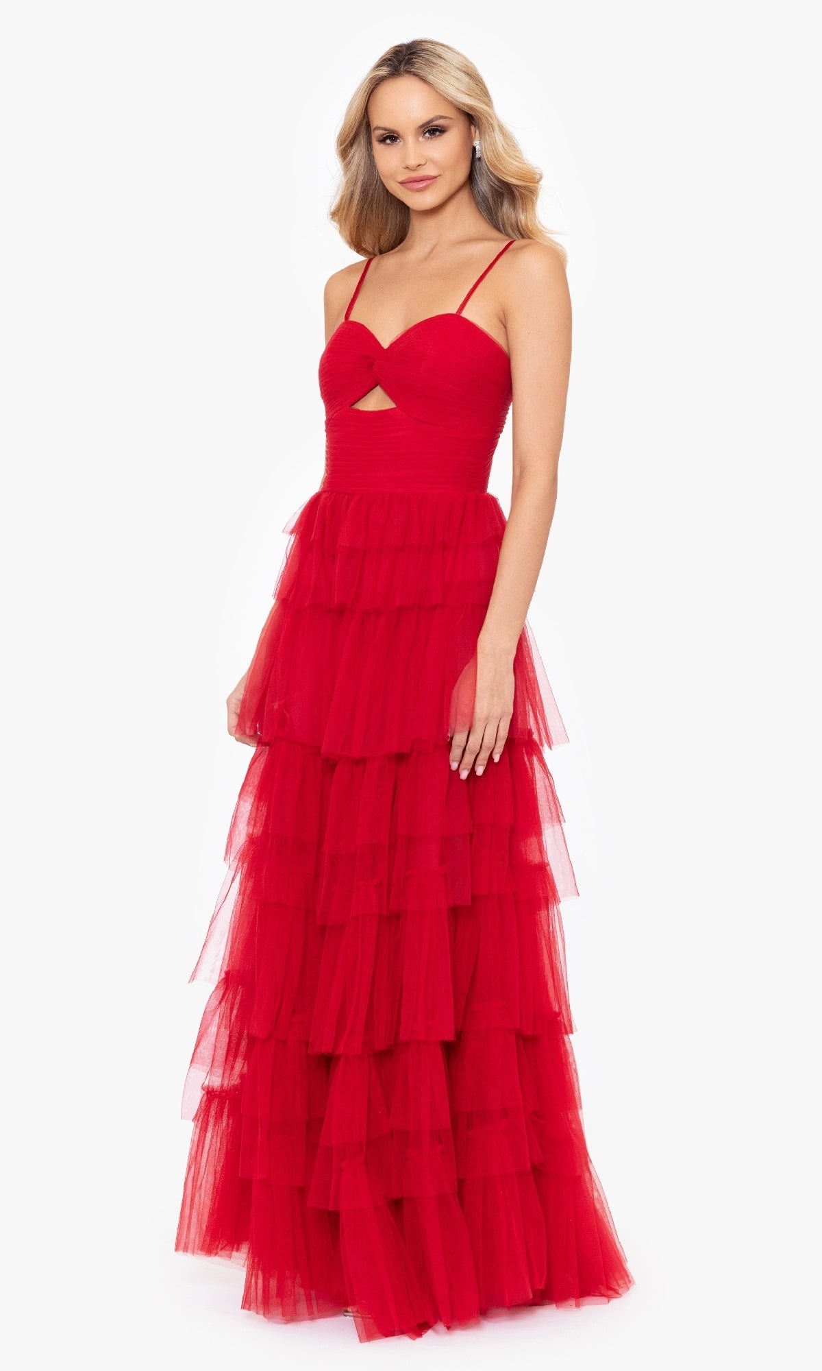 A woman models the Blondie Nites 4637BN Long Ruffled Prom Dress—sleeveless, red, with a sweetheart bodice, tiered tulle layers, thin straps, and a lace-up back—against a plain white background.