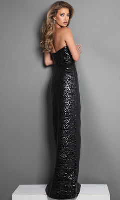 A woman wearing the Jovani 46579 long formal dress—strapless, floor-length, and black with a floral textured pattern—stands on a white platform, shown in profile against a gray background. This sophisticated ensemble highlights the elegance of this Jovani designer creation.